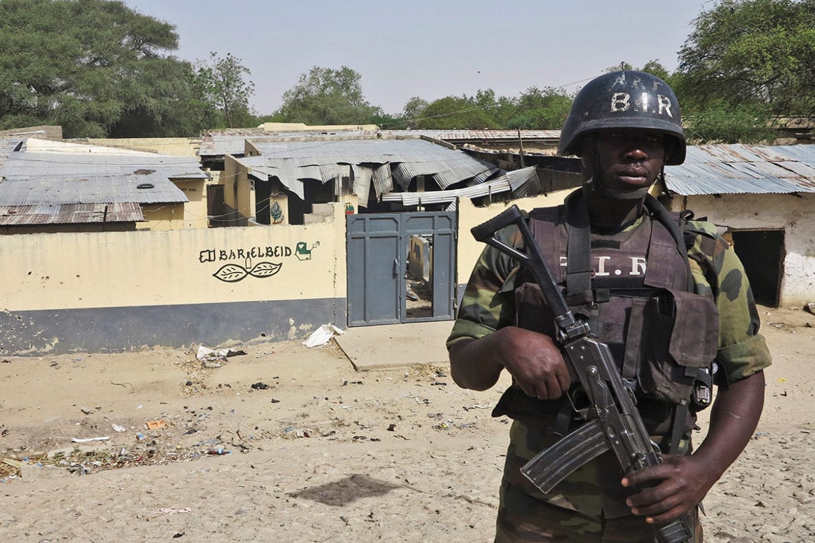 A Cameroon special forces soldier stands in front of a bar near the Elbeid bridge that was destroyed by Boko Haram assailants, in Fotokol