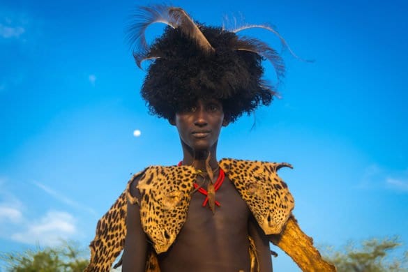 Dassanech man with leopard skin and ostrich feathers headwear during dimi ceremony to celebrate circumcision of teenagers, Omo valley, Omorate, Ethiopia
