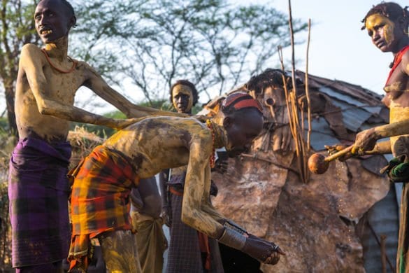 A dassanech man puts some mud on his friend body to join the dimi ceremony, Omo valley, Omorate, Ethiopia