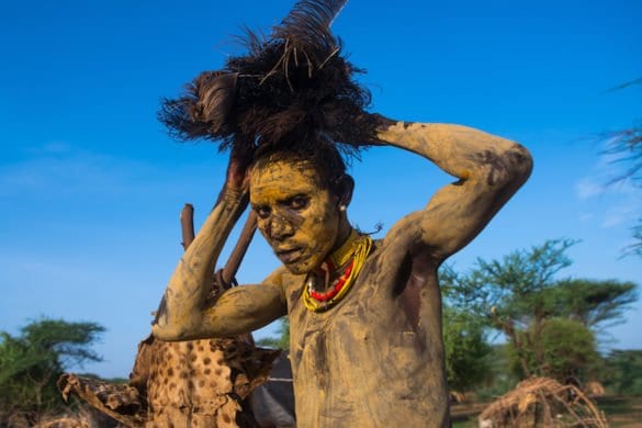 Dassanech man dressing with an ostrich feathers headwear for dimi ceremony to celebrate circumcision of the teenagers, Omo valley, Omorate, Ethiopia