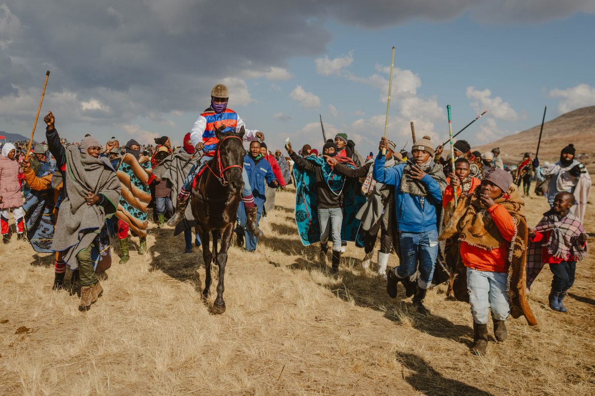 Gli spettatori esultano per la vittoria di un fantino all’annuale corsa di cavalli a Semonkong, Lesotho, il 19 luglio 2025. L’evento, tra i più attesi del Paese, si tiene ogni anno il primo sabato dopo il compleanno di re Letsie III. Foto di Fredrik Lerneryd / Afp