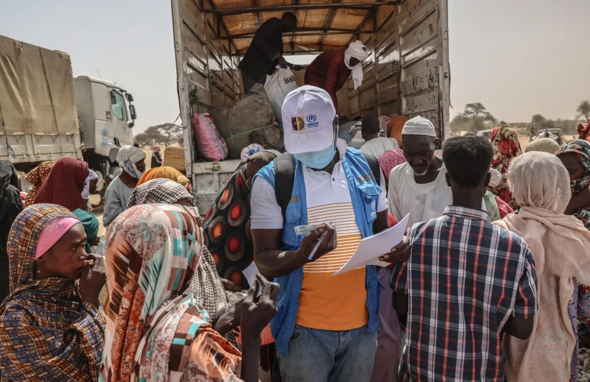 Un membro del personale dell'UNHCR controlla i documenti dei rifugiati appena arrivati dalla regione sudanese del Darfur settentrionale in un sito di transito vicino al valico di frontiera di Tine, in Ciad. © UNHCR/Caitlin Kelly