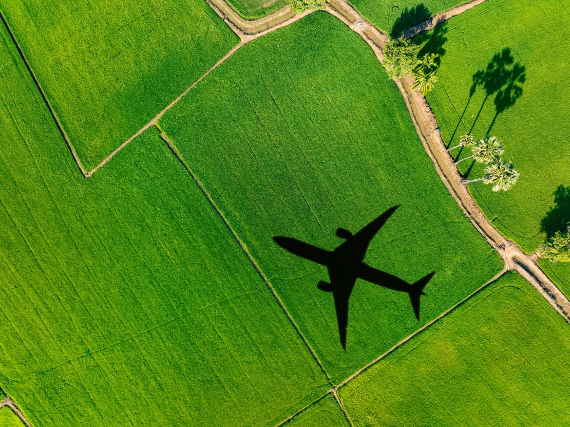 L'ombra di un aereo sorvola un campo verde.