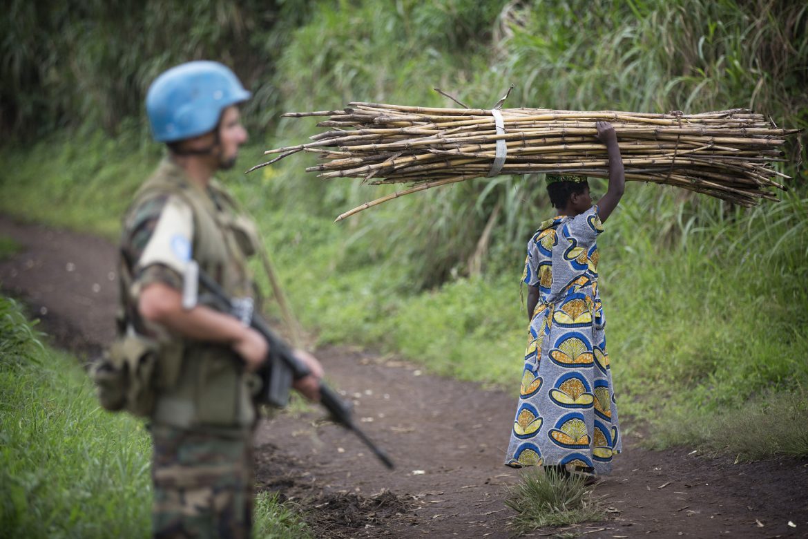 A peacekeeper on patrol as a resident gathers wood in the Beni region. Credit: UN Photo/Sylvain Liechti